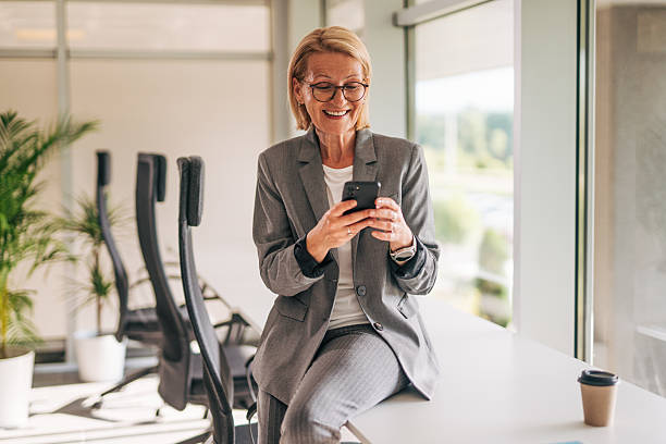 istock Smiling senior businesswoman using smartphone in modern office 2215029554