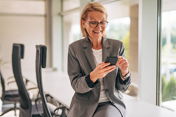 istock Smiling senior businesswoman using mobile phone in office 2215029559