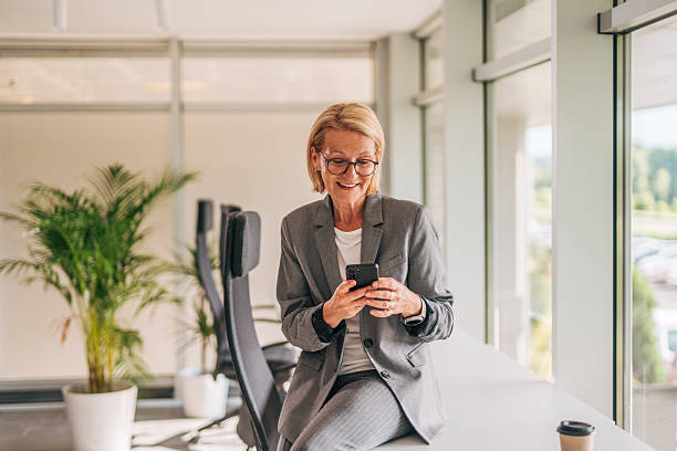 istock Smiling senior businesswoman using smartphone in modern office 2215029680