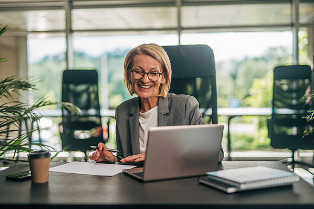 istock Senior businesswoman smiling while working on laptop in office 2215029747