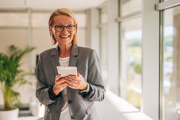 istock Senior businesswoman smiling and using digital tablet in office corridor 2215029864