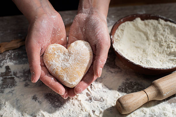 istock Baking concept. Caucasian female hands holding heart shaped dough. 2215030427