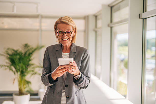 istock Smiling senior businesswoman using digital tablet in office hallway 2215030817