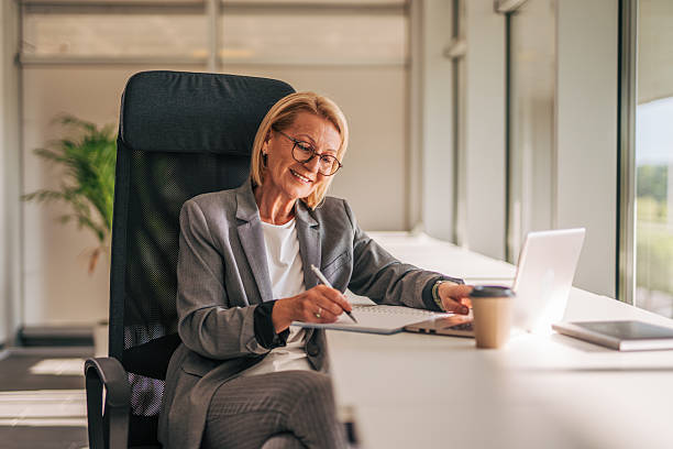 istock Senior businesswoman working on laptop and taking notes in modern office 2215031494