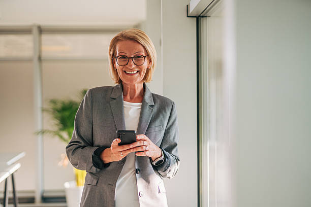 istock Smiling senior businesswoman using smartphone in modern office 2215032491