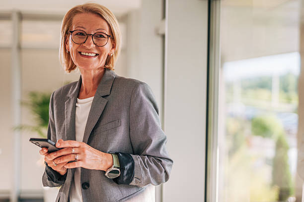 istock Smiling senior businesswoman using smartphone in modern office 2215032495