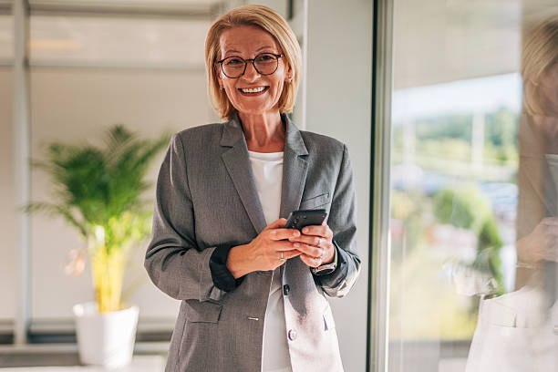 istock Senior businesswoman smiling and using mobile phone in office 2215032501