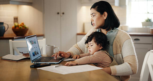 istock Multitasking, child and mom with laptop, remote work and editing article in kitchen with baby or online. Serious, writer and woman with toddler in house, screen and person with project for blog 2215035013