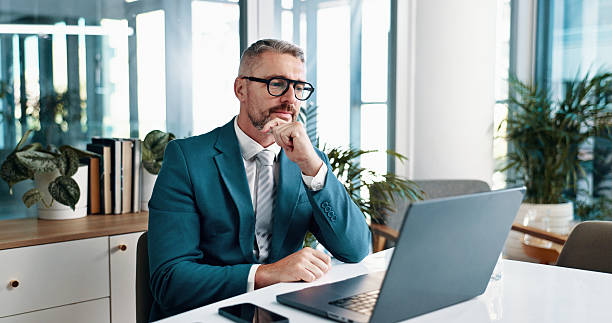istock Businessman, thinking and reading on laptop for problem solving, investment idea or evaluation. Computer, mature and corporate manager with financial email for decision, planning or insight in office 2215035130