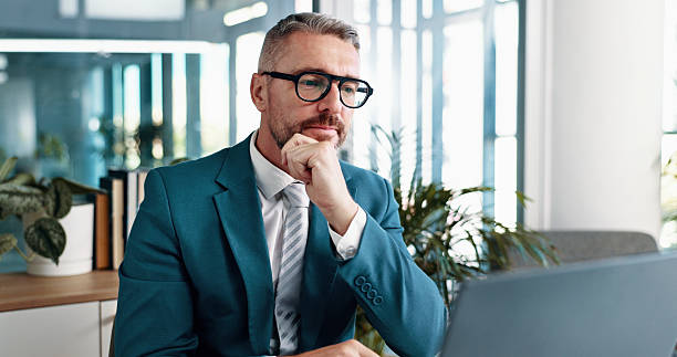 istock Business man, thinking and reading on laptop for problem solving, investment idea or evaluation. Computer, mature or corporate manager with financial email for decision, planning or insight in office 2215035145