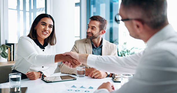 istock Business people, meeting or shaking hands with finance report documents for b2b proposal. Analyst, graphs and staff in office for planning with handshake for merger, accounting team or profit growth 2215035203