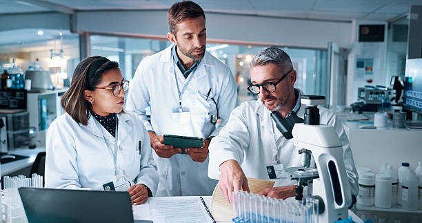 istock Collaboration, science and teaching with people in laboratory together for breakthrough or development. Laptop, microscope or tablet and research team with mentor in clinical trial for medical study 2215035724