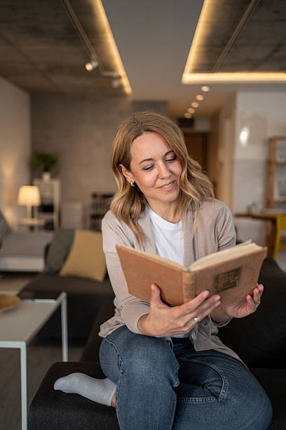 istock Woman reading a book at home on the sofa 2215036433