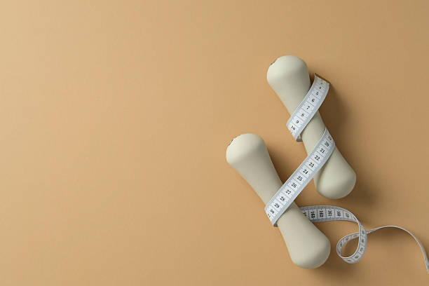 istock Dumbbells and measuring tape on a beige background. 2215036973