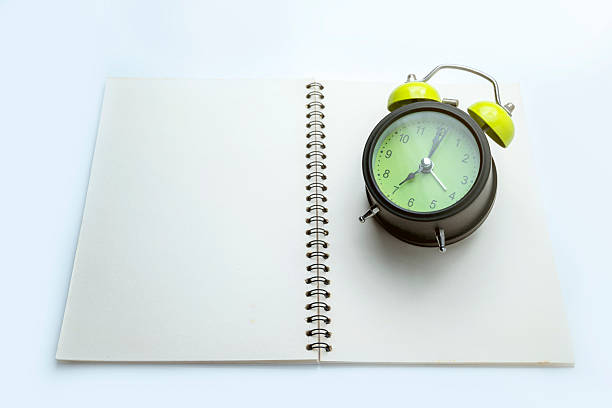istock Green alarm clock and notebook on white background. Empty area for mockup or copy space. Concept of study or education 2215040471
