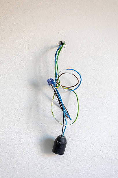 istock Electrical wires coming out of a hole in a white wall with lightbulb socket 2215041241
