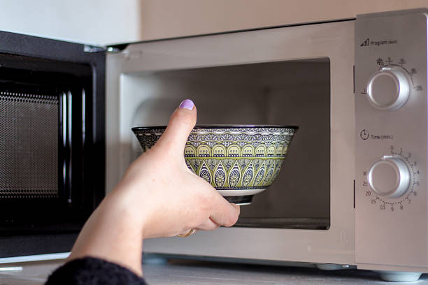 istock Woman placing bowl in microwave 2215041655