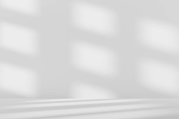 istock 3D white studio room with a window shadow on the wall. Sunlight moves across the empty room. Grey background for product display, with space for text. 2215042876