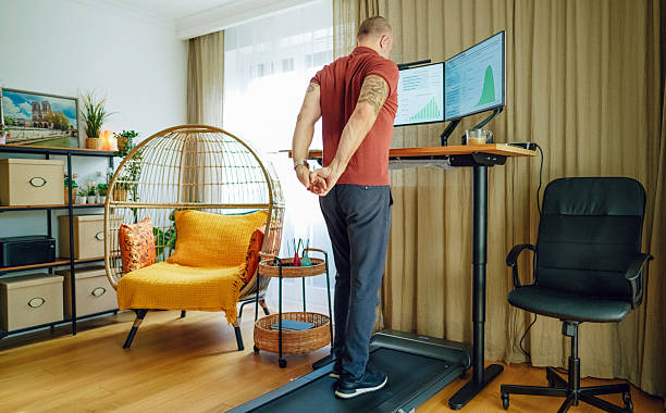istock Man stretching at standing desk with treadmill in home office 2215046496