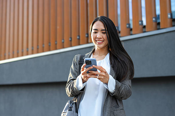 istock Smiling professional woman browsing on a smartphone outdoors near a modern building 2215048783