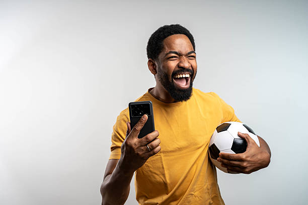 istock Excited young black man winner using smartphone isolated on grey background. 2215048884
