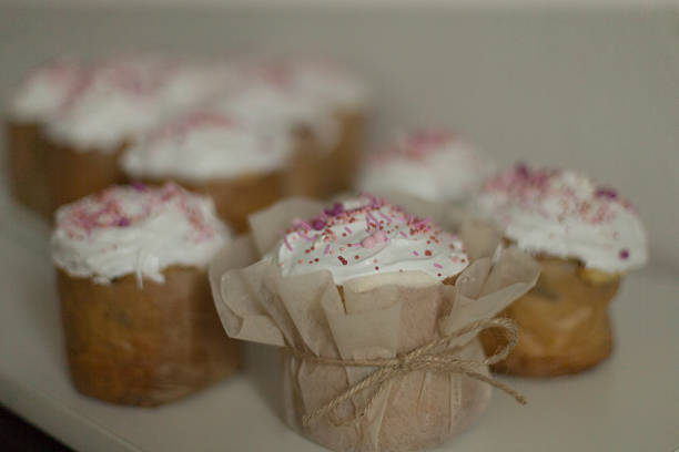 Freshly baked cupcakes with cream frosting and colorful sprinkles on a neutral background.
