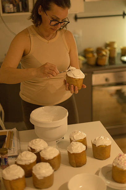 istock Baker Decorating Cupcakes in Kitchen with Frosting and Background 2215054299
