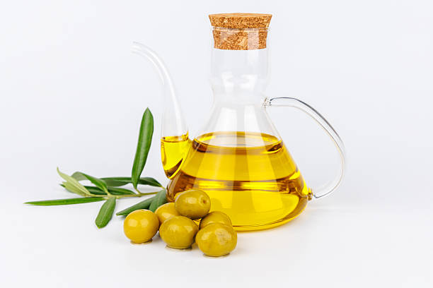 istock Fresh olive oil and green olives next to olive branches on a white minimalist surface 2215055620