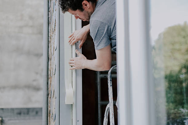 istock One young worker repairs window frames by gluing on tape. 2215055668