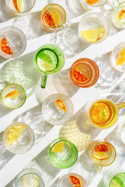 istock Vivid Glasses with cold detox water as summer still life pattern, shadow and sunlight refraction, closeup glass cups of infused fruit water, slises of lemon, orange, healthy summer drink 2215062775