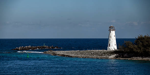 Lighthouse, early morning, Paradise Island, Nassau, Bahamas, photographed from a cruise ship as it enters the harbor.  Lighthouse in a state of disrepair.  Photographed in March 2025.