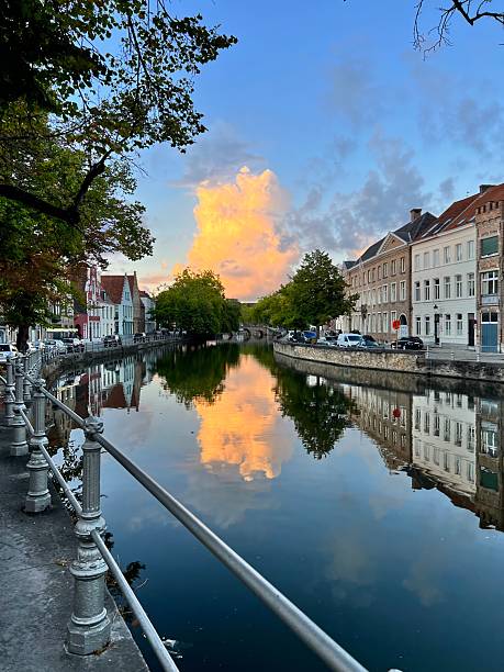 istock Beautiful evening scene in Bruges, Belgium, featuring a canal lined with charming historic buildings and a dramatic sky reflection in the water. 2215065254