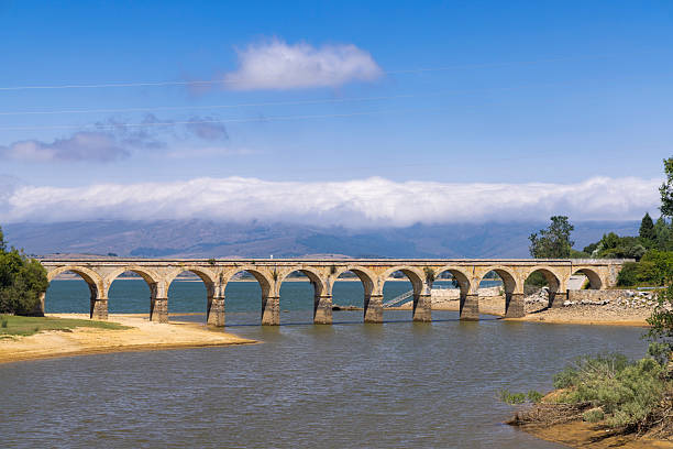 istock Old stone bridge crossing a reservoir in Arija, Spain, under a cloudy sky 2215065499