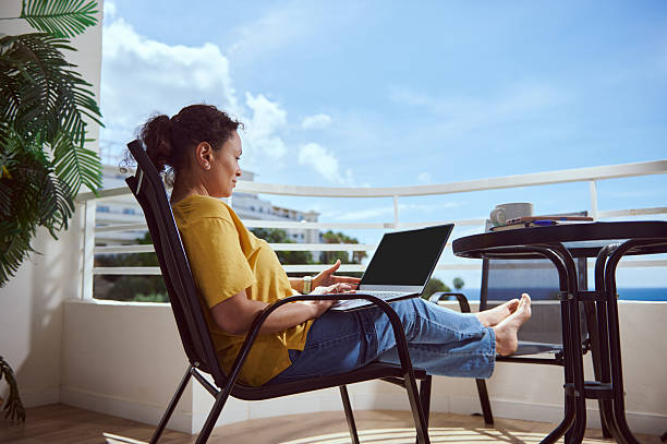 istock Woman Working Remotely on a Laptop at a Balcony with Ocean View 2215065777