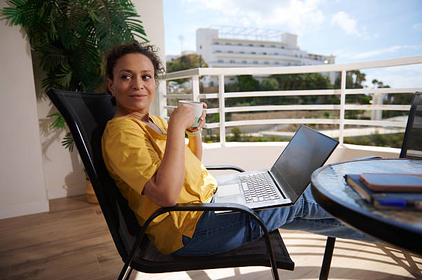 istock Woman Relaxing Outdoors With Coffee and Laptop on a Balcony 2215065869