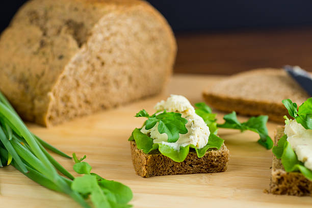 Close up detail of homemade spreadable cheese made of organic kefir drink, wholemeal bread and fresh spring onions - healthy nutrition concept