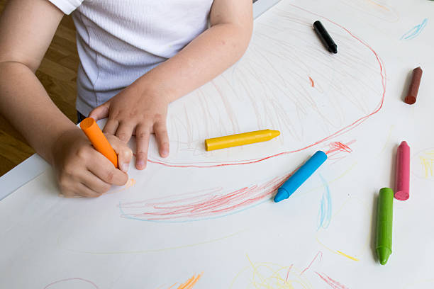 istock Young child drawing with colorful crayons on white paper 2215068902