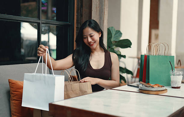 istock Happy customer checking purchases at a cafe table after enjoying a shopping spree, savoring her coffee and relaxing outdoors 2215069214