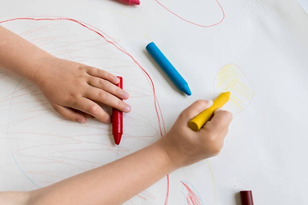 istock Child drawing with colorful crayons on white paper 2215070227