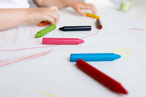 istock Child drawing with colorful crayons on white paper 2215071224