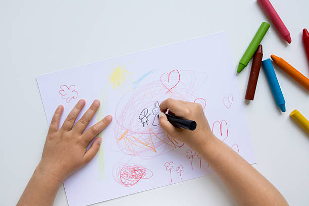 istock Child drawing with colorful crayons on white paper 2215071231