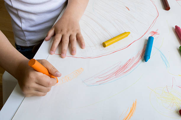 istock Child drawing with colorful crayons on paper 2215071235
