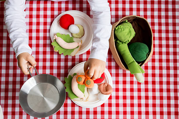 istock Child playing with colorful felt vegetables on red checkered tablecloth 2215071242