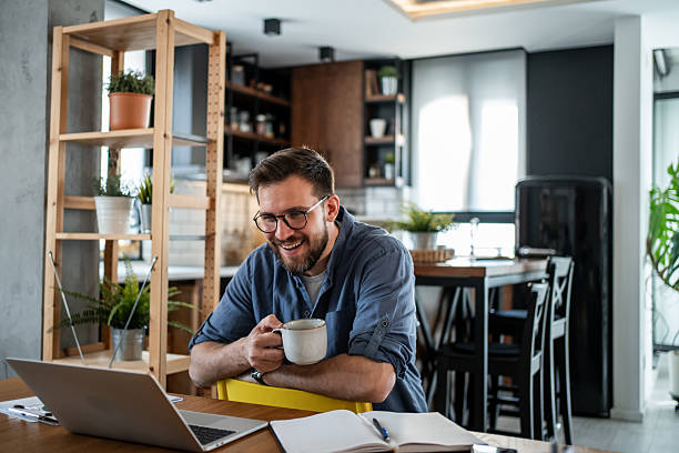 istock Young man working remotely from home and drinking coffee 2215071292