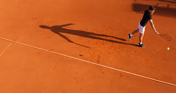 istock Tennis Player Hitting Forehand on Clay Court with Visible Shadow 2215075194