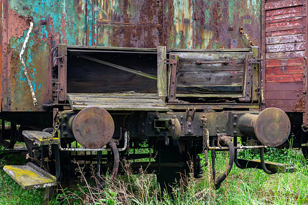 Rusty, abandoned freight train car standing on an overgrown railway track. Visible wear, corrosion, peeling paint, and decayed wooden elements reflect the passage of time and the decline of rail transport. Atmospheric image capturing the theme of industrial decay and nostalgia for the past.