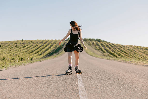 istock Brunette young woman training on roller skating outdoor on road 2215077259