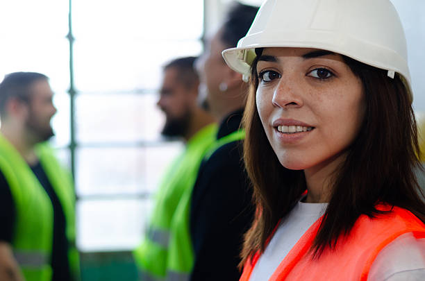 istock Smiling confident woman in safety gear at work site with workers behind 2215078605