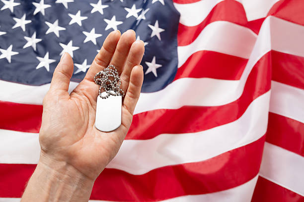 istock Hand Holding Dog Tags Against American Flag Background 2215078843