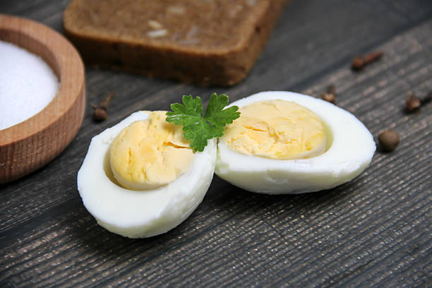 Two halves of a boiled egg on a dark wooden background